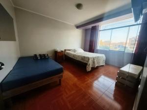 a bedroom with two beds and a large window at APART TOSCANO Suites in Huancayo