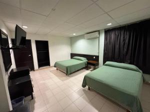 a hospital room with two beds and a flat screen tv at Hotel y Restaurante Ritz de Tabasco in Villahermosa