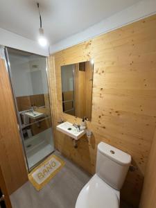 a bathroom with a toilet and two sinks and a mirror at O Refuxio de Loira in Valdoviño