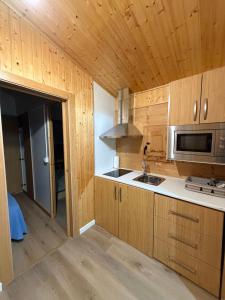a kitchen with wooden cabinets and a microwave at O Refuxio de Loira in Valdoviño