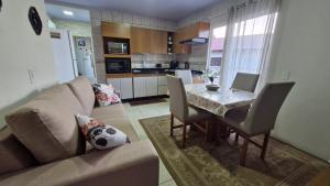 a living room with a couch and a dining room table at Casa Beira Mar Mariscal Superior in Bombinhas