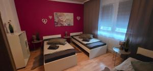 a room with two beds and a purple wall at Ferienwohnung FeLuMi in Wadgassen
