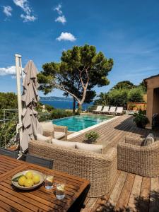 a patio with a table and chairs and a swimming pool at Villa Bellevue, magnifique vue mer! Piscine chauffée, à10 mns de la plage et du centre! in Cavalaire-sur-Mer