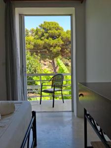 a bedroom with a bed and a chair on a balcony at Ellia Mirtiotissa Rooms in Glyfada