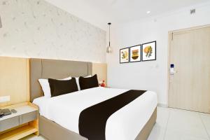 a bedroom with a large white bed with black pillows at Townhouse Oak AECS Layout Brookfield in Bangalore