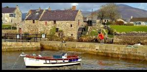 a boat is docked in the water next to a house at Harbour Mill Cottage in Annalong