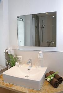 bagno con lavandino bianco e specchio di Goldener Schlüssel mit Gästehaus Sina a Nördlingen