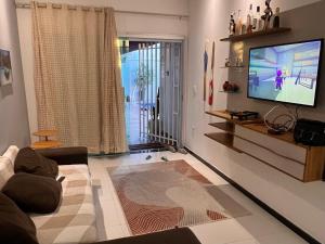 a living room with a couch and a flat screen tv at Casa inteira com Piscina - 3 Quartos - Área Gourmet - 5 min da Praia in Prado