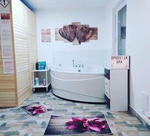 a bathroom with a bath tub and pink flowers on the floor at SPA apartman in Kragujevac