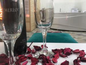 a bottle of wine and a wine glass and red rose petals at SPA apartman in Kragujevac