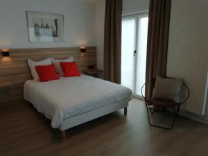 a bedroom with a bed with red pillows and a chair at LEHOUCK kamers ontbijt in Koksijde