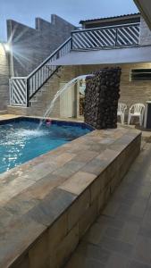 a swimming pool with a staircase and a water fountain at Linda casa Edícula "fundos do terreno" com piscina in Itanhaém