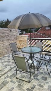 a table and chairs with an umbrella on a patio at Linda casa Edícula "fundos do terreno" com piscina in Itanhaém
