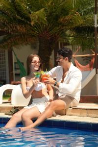 a man and a woman sitting next to a swimming pool at Pousada Villa Mar Porto in Porto De Galinhas