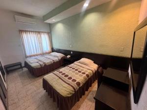 a hotel room with two beds and a window at Hotel y Restaurante Ritz de Tabasco in Villahermosa