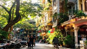 people walking and riding bikes down a street with buildings at Hanoi Discovery Travel Hotel in Hanoi