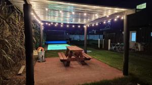 a wooden picnic table under a pergola with lights at Las Marinas Playa Grande 1 in Piriápolis