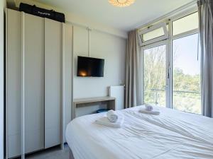 a bedroom with a white bed and a window at Coastal Escape w Sauna in Zoutelande