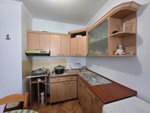 a small kitchen with wooden cabinets and a sink at APP Apartament in Durrës