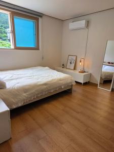 a bedroom with a large bed and a window at Aju Good House 아주굿하우스 in Geoje +18 photos