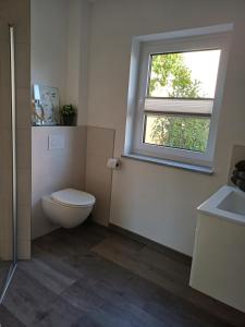 a bathroom with a toilet and a window at Ferienwohnung BlumenMeer in Karlshagen +13 photos