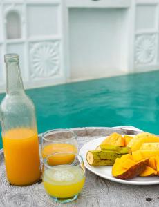 a table with a bottle of orange juice and a plate of fruit at Kilele House in Lamu