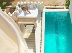 a woman laying on a bed next to a swimming pool at Kilele House in Lamu