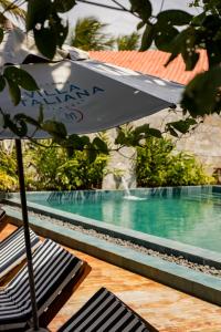 an umbrella sitting next to a swimming pool at Pousada de Charme Villa Italiana - Pé na Areia in São Miguel dos Milagres