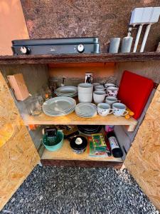 a shelf with pots and pans and dishes on it at Glamping 68 - Summer cottage in Kámen