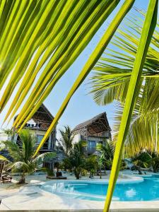a view of the resort from the beach with palm trees at Mfumbwi Twins Villa in Jambiani