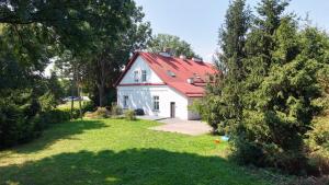 a white house with a red roof in a yard at Apartamenty Trzciana in Rzeszów