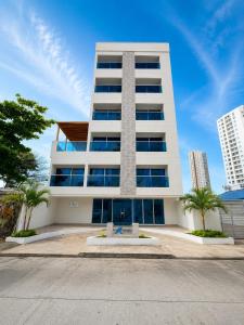 a tall white building with palm trees in front of it at Hotel Azure Cartagena in Cartagena de Indias
