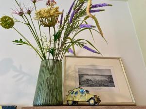 a vase with flowers and a toy car on a table at the window in Domodossola