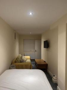 a bedroom with a bed and a couch in it at Quiet Double Room Ensuite Marble Bathroom South Croydon in Croydon