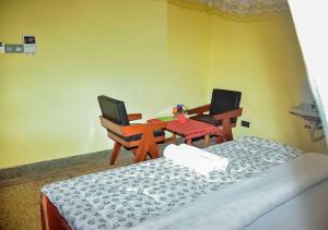a room with two beds and a desk and a table at Safari Resot Star One in Moshi