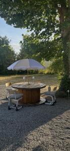 a wooden table with two chairs and an umbrella at Le Nid de Lou in Aire