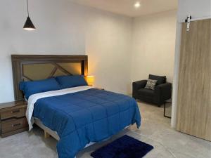 a bedroom with a blue bed and a chair at Suite privada con alberca - Cama Queen in El Centenario