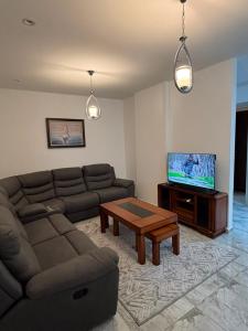 a living room with a couch and a table and a tv at Bel appartement in Cheraga