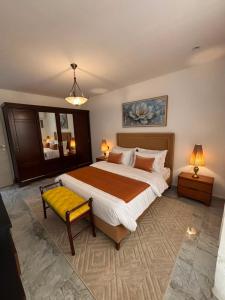 a bedroom with a large bed and a yellow bench at Bel appartement in Cheraga