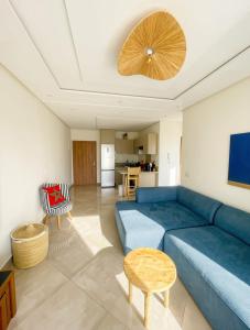 a living room with a blue couch and a kitchen at 2BR Pool View Kids Pool & Gym 6 Min to Beach in Dar Hamida