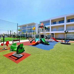 a playground in front of a large building at 2BR Pool View Kids Pool & Gym 6 Min to Beach in Dar Hamida