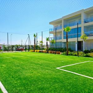 a tennis court in front of a building with palm trees at 2BR Pool View Kids Pool & Gym 6 Min to Beach in Dar Hamida