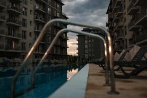 a metal hand rail next to a pool with buildings at Seyra Olive Studio in Ştefăneştii de Sus