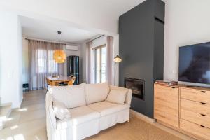 a living room with a white couch and a tv at Villa Gagra - Villa by the Sea with a Private Pool in Panormos Rethymno