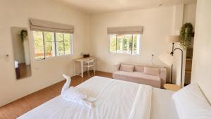 a white bedroom with a bed and a chair at Zen Village in Ko Phangan