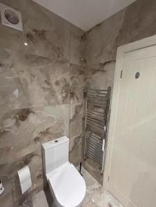 a bathroom with a toilet and a stone wall at Quiet Double Room Ensuite Marble Bathroom South Croydon in Croydon