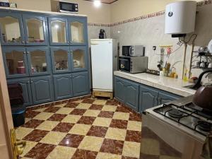 a kitchen with blue cabinets and a white refrigerator at Omarkad in Taourirt