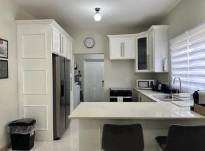 a kitchen with white cabinets and a clock on the wall at Villa cool breeze in Steer Town +1 photo