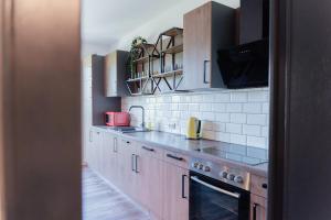 a kitchen with wooden cabinets and white tiles at MiHome - Grimming View Apartment in Tauplitz