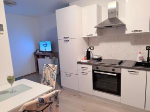 a kitchen with white cabinets and a stove and a table at Apartmani G&E in Delnice